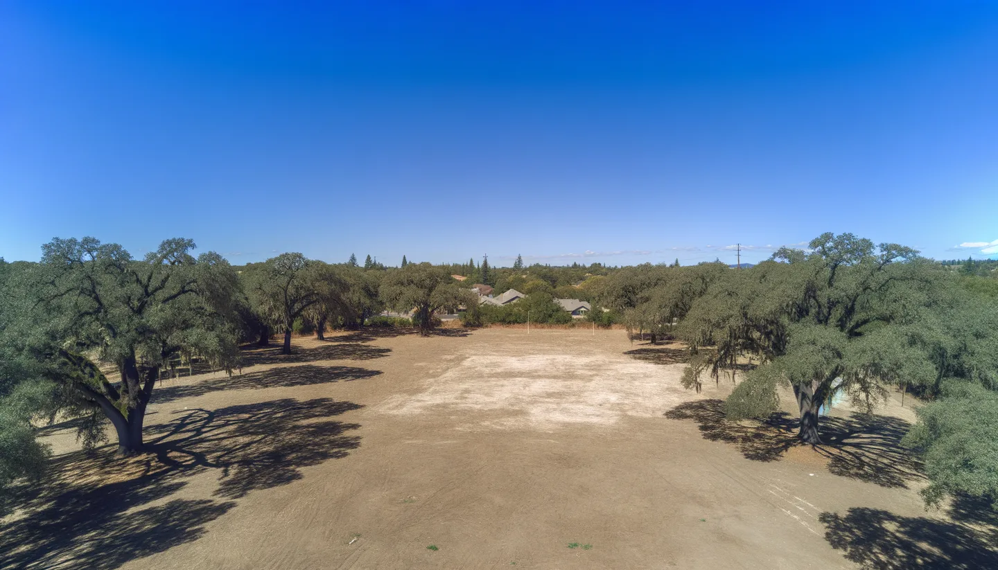 Aerial view of a cleared vacant lot bordered by oak trees in California